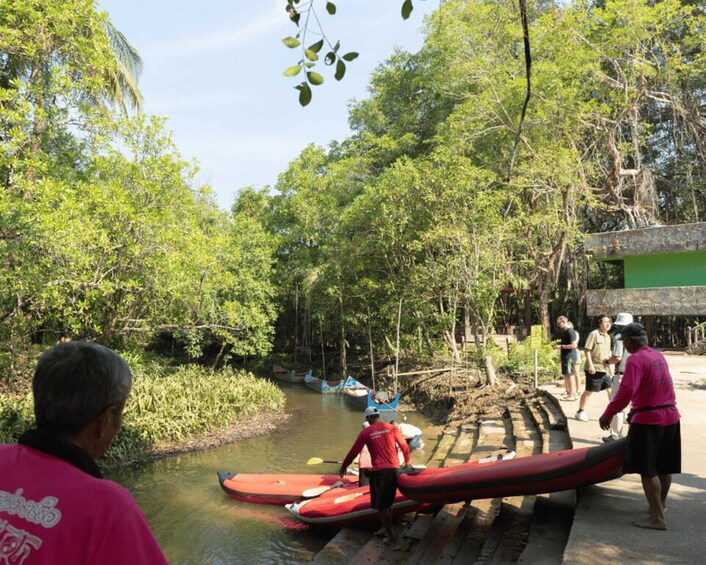 A riverbank with canoes, people, and a bridge. 2
