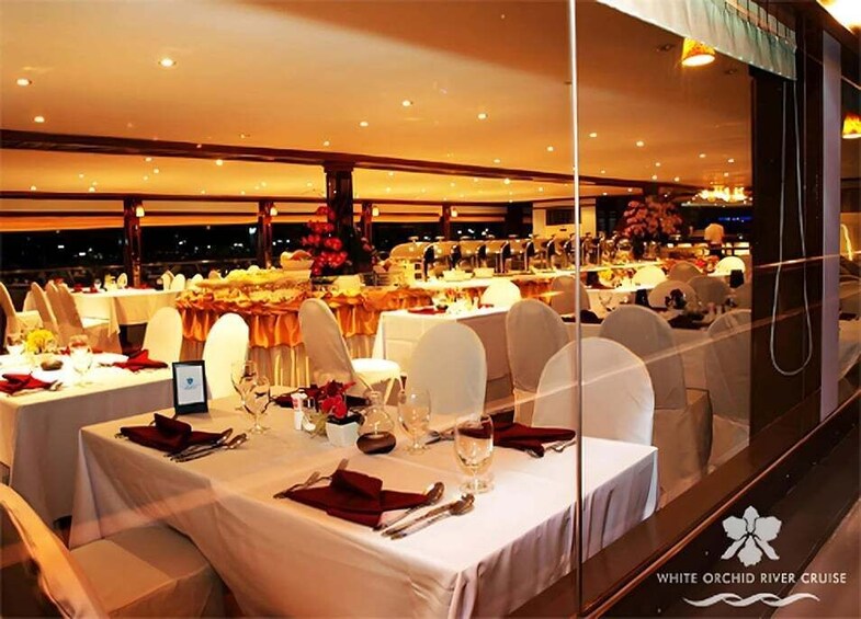 Un salón de banquetes con mesas dispuestas para un evento formal, sillas blancas y un gran arreglo floral. 4