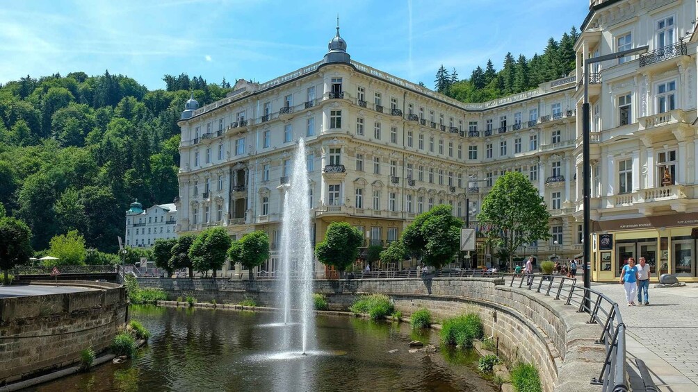 A historic building with a fountain in front, surrounded by trees and a body of water. 2