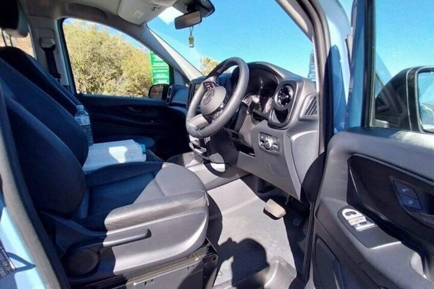 A car's interior with a steering wheel, dashboard, and seats. 4