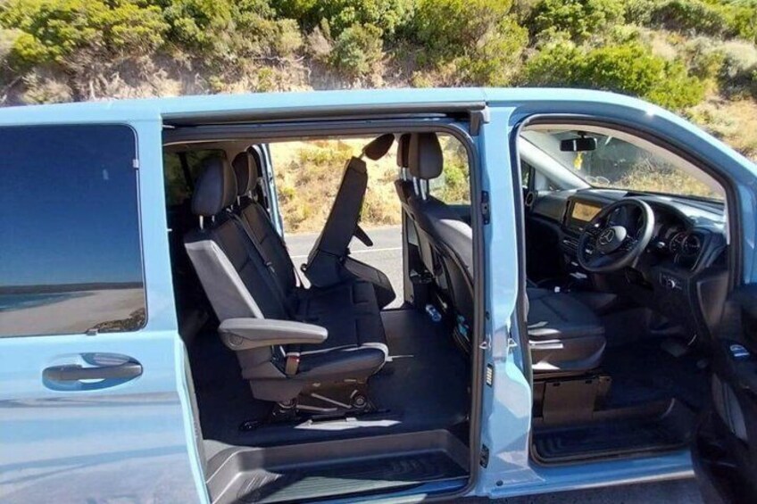 A vehicle interior with a driver's seat, steering wheel, dashboard, and a rear view of the back seat. 2