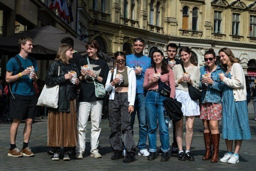 Un groupe de personnes se tient dans une rue de la ville, certaines tenant de la nourriture. 1