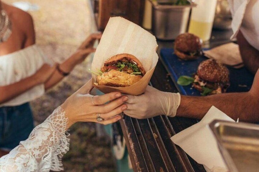 Une personne tient un hamburger emballé dans du papier, tandis qu’une autre personne le lui tend. 2