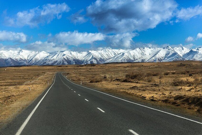 A road leading to snow-capped mountains under a clear sky. 3