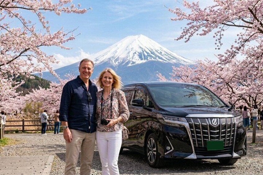 Una pareja parada frente a un coche con una montaña al fondo. 1