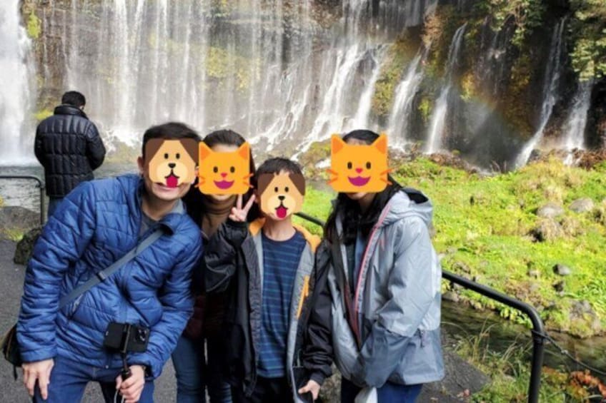 Un grupo de personas frente a una cascada, con alguien fotografiando. 4