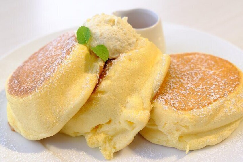 Pancakes with syrup and powdered sugar, a small cup, and a mint leaf garnish. 4