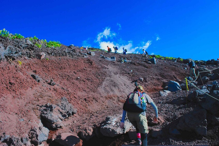 A hiker ascending a steep, rocky slope with sparse vegetation. 5