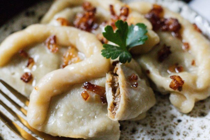 Un plato de pierogi con una guarnición de perejil y trozos crujientes de tocino. 1