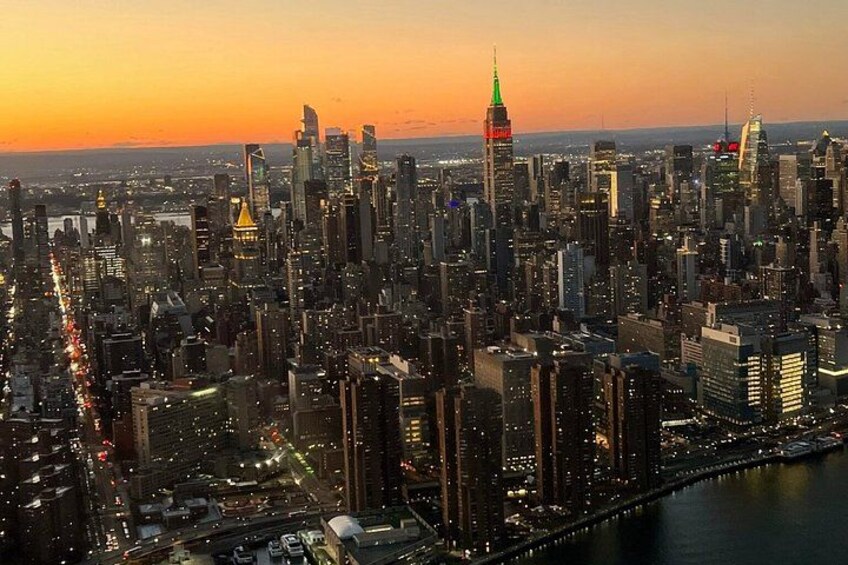 A city skyline at sunset with prominent skyscrapers and a river. 2