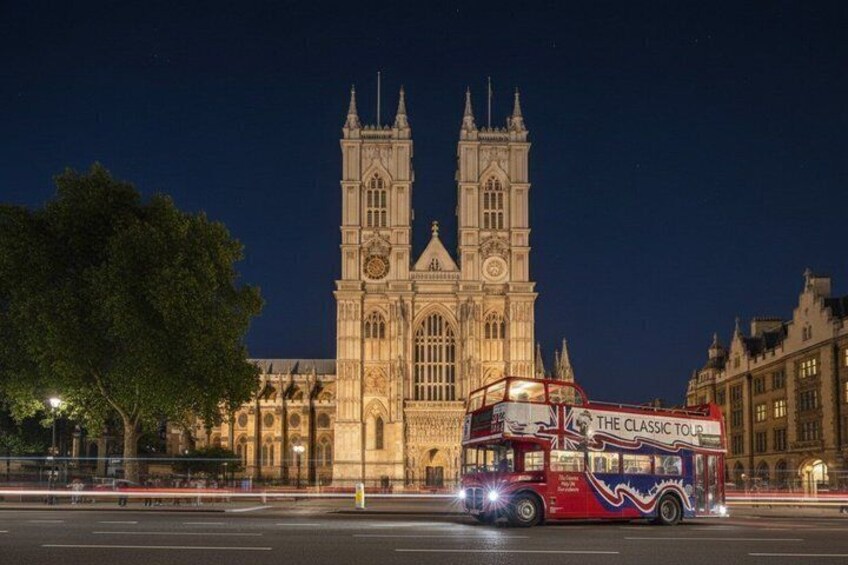 A double-decker bus with 'The Classic Tour' written on it, in front of a large, illuminated cathedral at night. 5