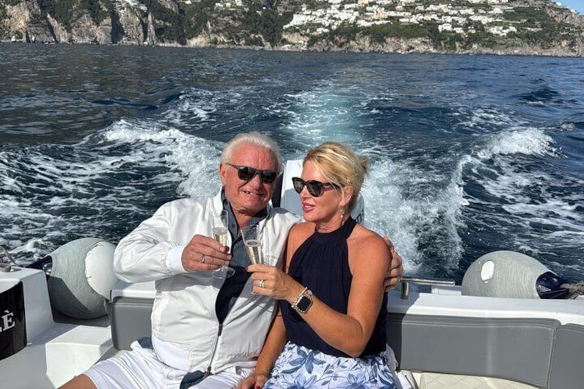 Dos personas en un bote con un litoral rocoso al fondo. 5