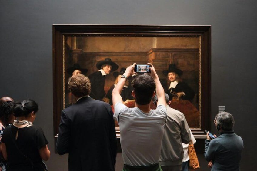 Persone che scattano fotografie a un dipinto in un museo. 5