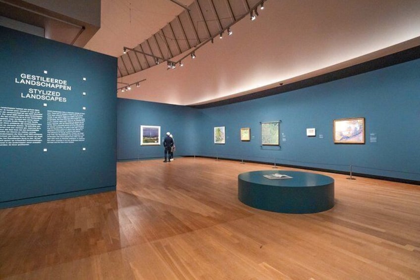 Una galleria d'arte con pavimenti in legno e pareti blu, con opere d'arte incorniciate e pannelli informativi. 2