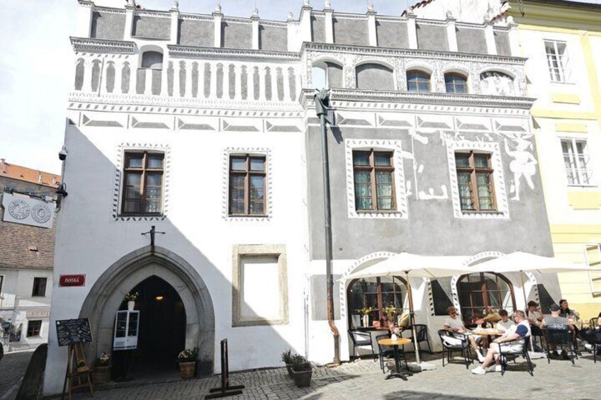 Un edificio histórico con arquitectura ornamentada, un café con terraza y una calle adoquinada. 3