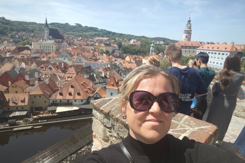 Una persona tomándose un selfie con un pueblo histórico y un río de fondo. 1