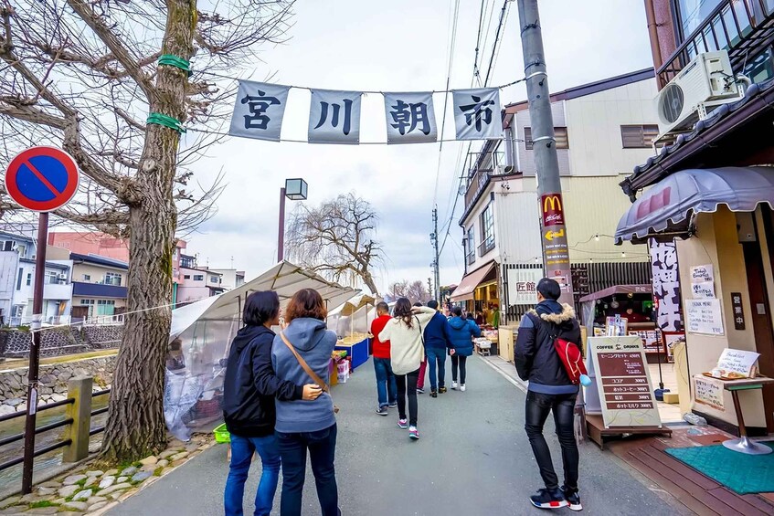 A street with a no parking sign, a tree, and people walking. 2