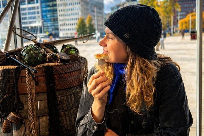 A person eating a pastry near a wooden barrel with green vegetables. 1