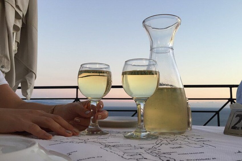 A person holding two wine glasses and a pitcher on a table with a map. 4