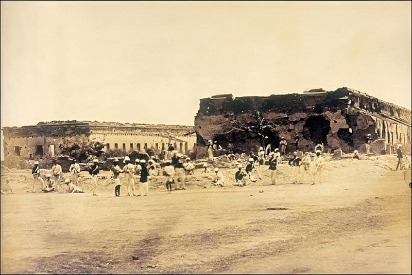 A historical site with ancient ruins and a large gathering of people. 2