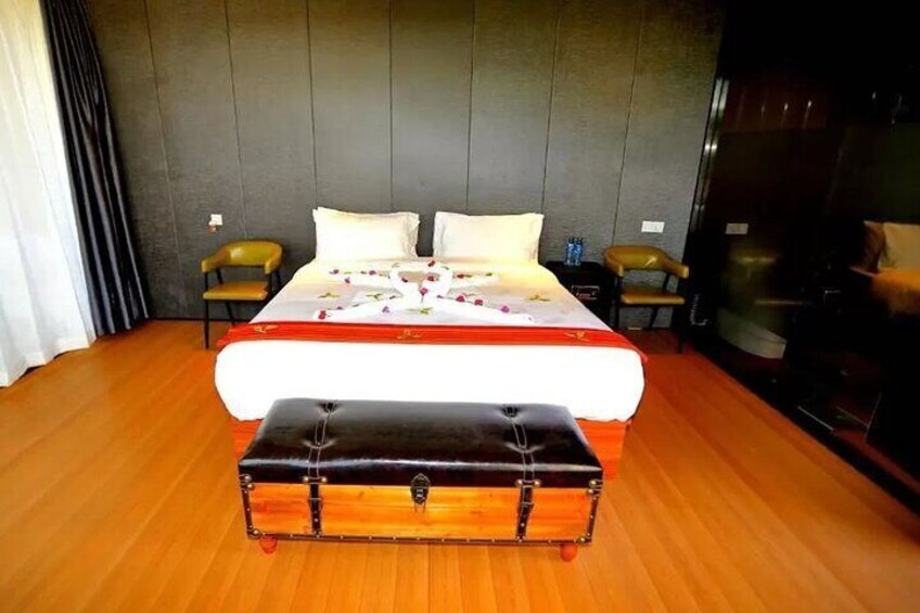 A hotel room with a large bed, wooden floor, and a chest of drawers. 5
