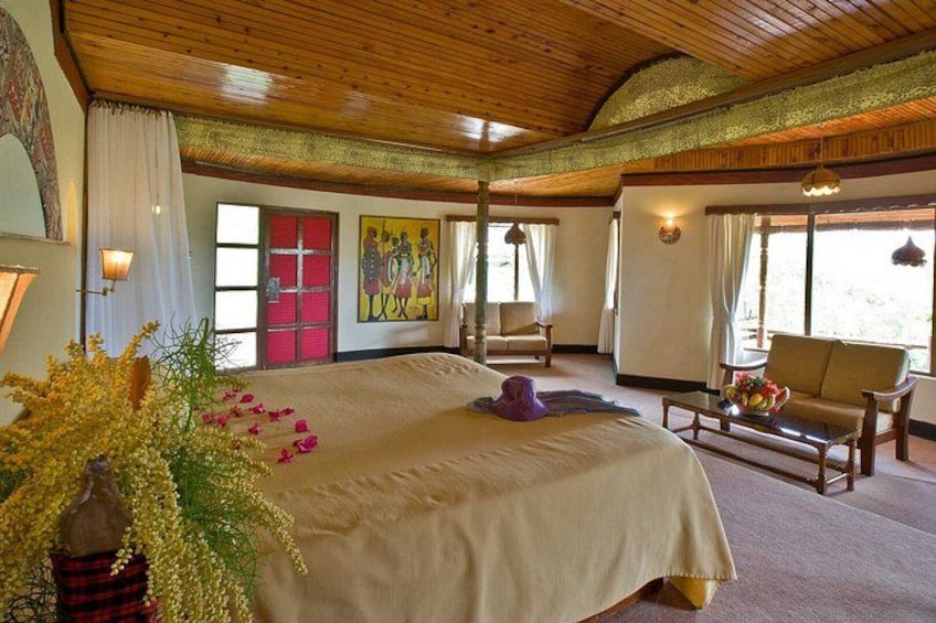 A spacious bedroom with a large bed, wooden ceiling, and a painting on the wall. 4