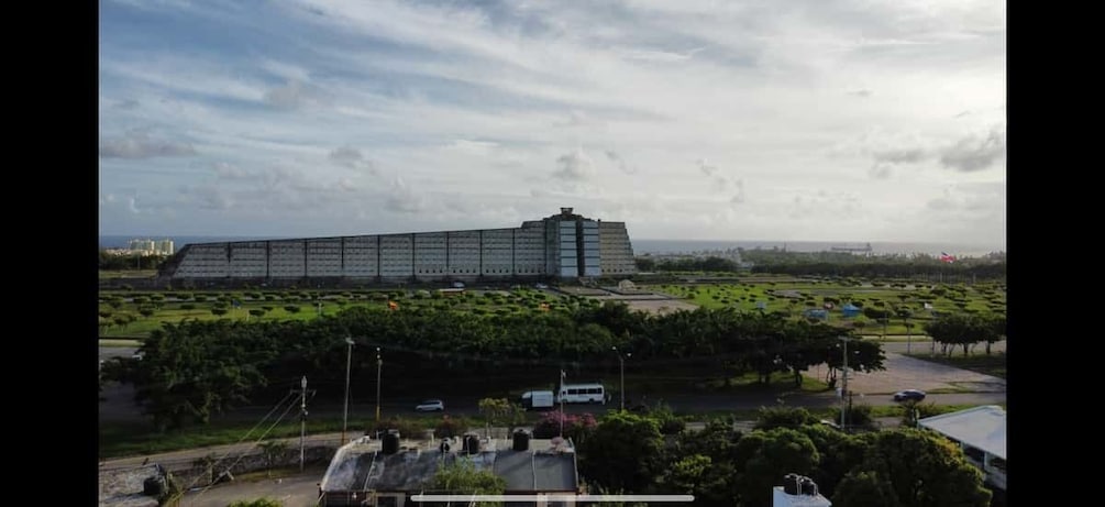 A large building with a flat roof, surrounded by green fields and trees. 3