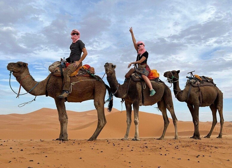 Three camels with riders in a desert landscape. 2