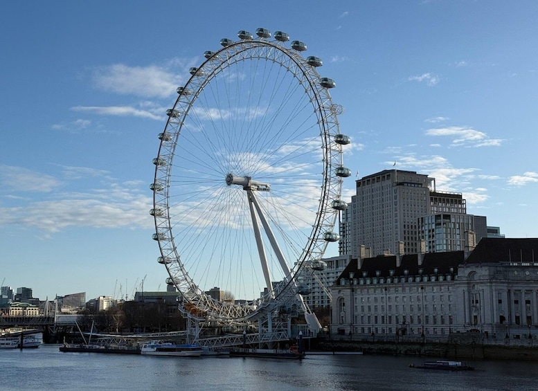 A large Ferris wheel with a river and buildings in the background. 4