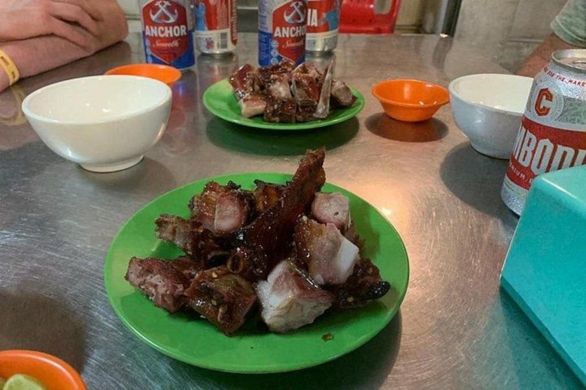 Una mesa con platos de carne a la parrilla, salsas y una lata de cerveza. 5