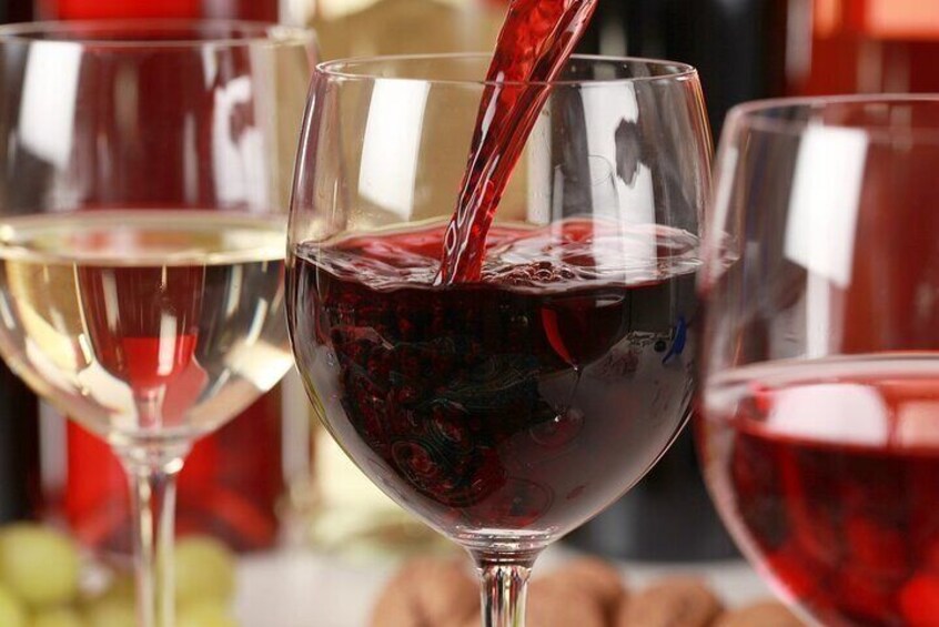A glass of red wine being poured into another glass. 4