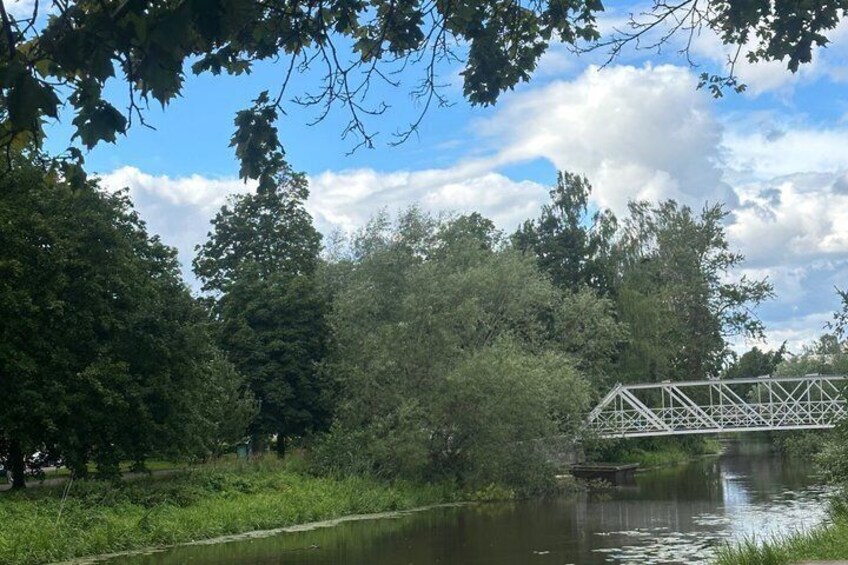 A river with a metal bridge, surrounded by dense trees and a clear sky. 2