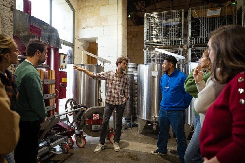 A group of people in a workshop with large metal tanks and machinery. 3