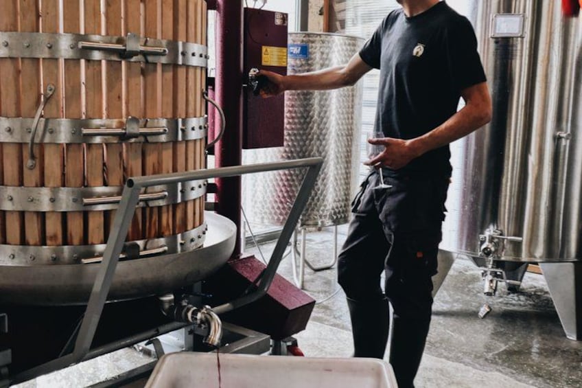 A person operating a large wooden barrel in a brewery setting. 2