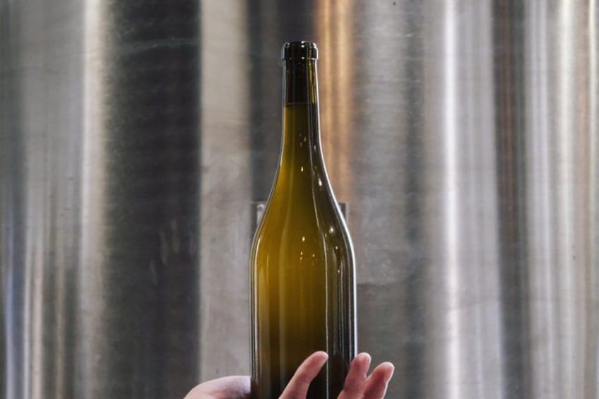 A hand holding a wine bottle against a stainless steel background. 3