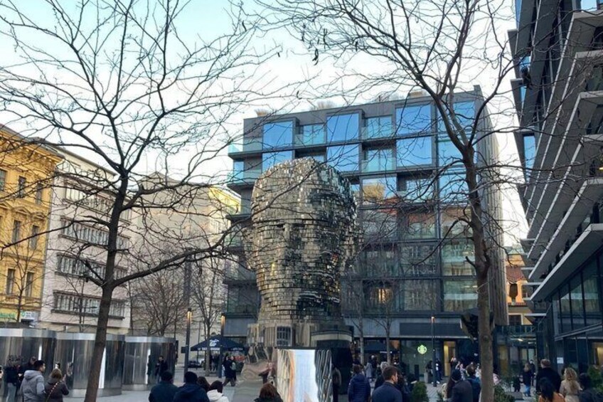 A modern sculpture in an urban plaza with people walking around. 5