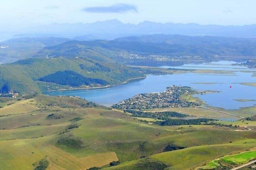 A hilly landscape with a lake, a small settlement, and distant mountains. 5