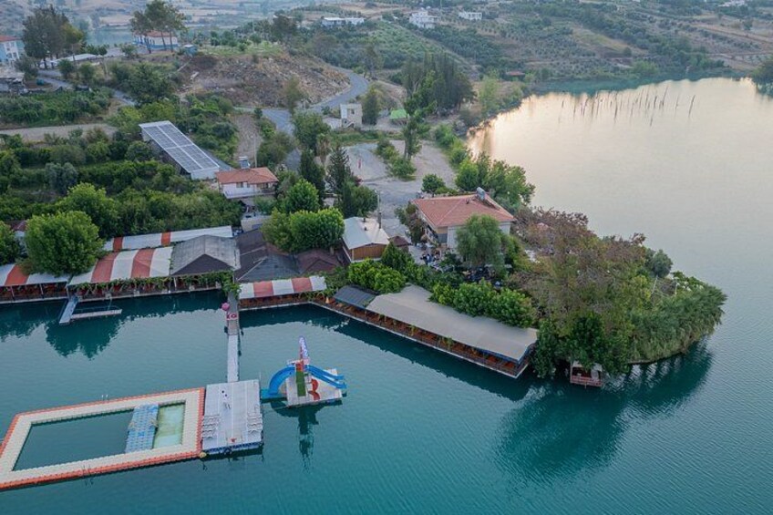 An aerial view of a lakeside area with a dock, buildings, and a small island. 3