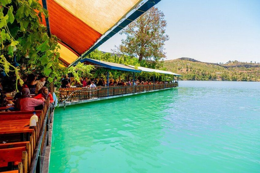 A boat tour on a turquoise lake with people seated under a canopy. 2