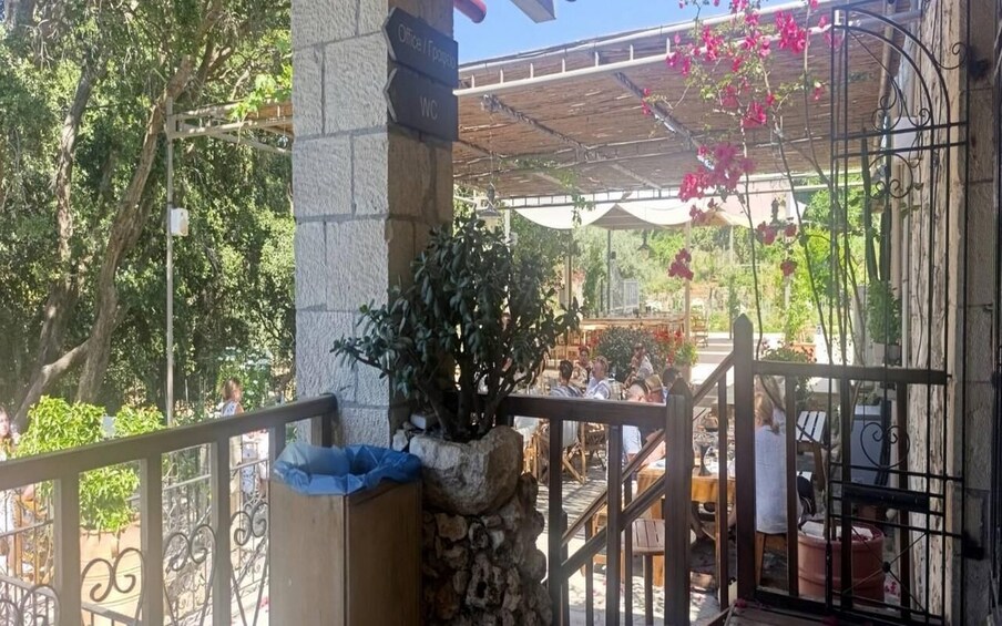 A covered outdoor seating area with stone pillars, a metal railing, and hanging pink flowers. 5