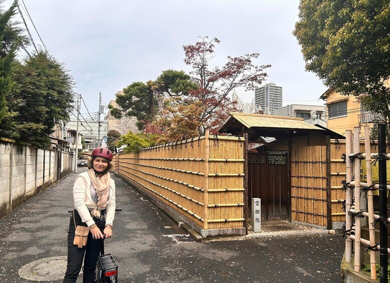 A person on a bicycle, a bamboo fence, and a traditional Japanese building. 2