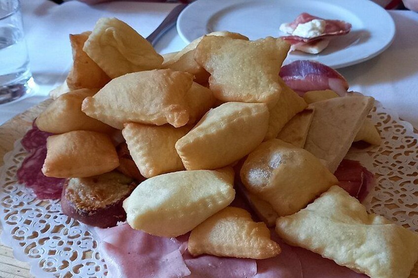 A plate of fried pastries and slices of ham. 2