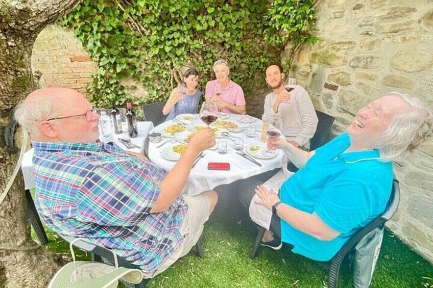 A group of people dining outdoors at a round table with food and drinks. 4