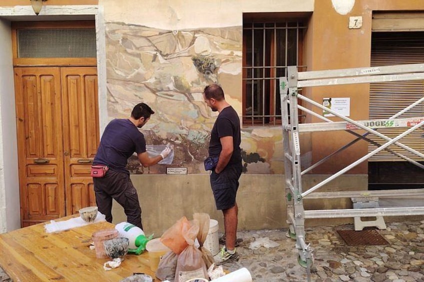 Two people painting a wall, a wooden door, and a metal scaffolding. 2