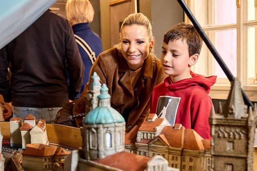 A person and a child examining a model building. 2