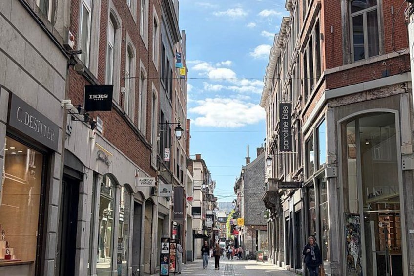 Une rue bordée de boutiques, dont un magasin C. Desitter et un service de vente de voitures en ligne. 3
