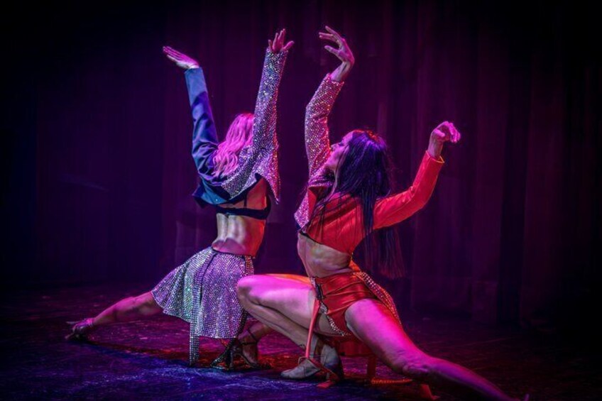 Two dancers in dynamic poses on a stage with a dark background. 5