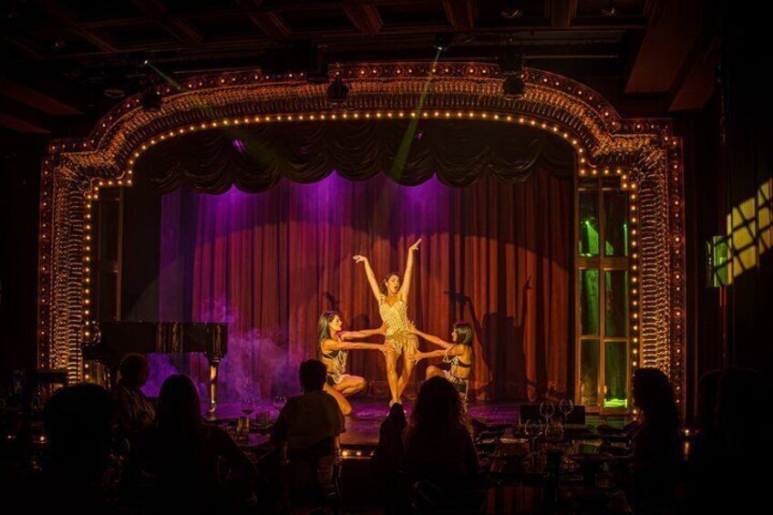 A stage with a performer in a dynamic pose, surrounded by an ornate frame and stage lights. 4