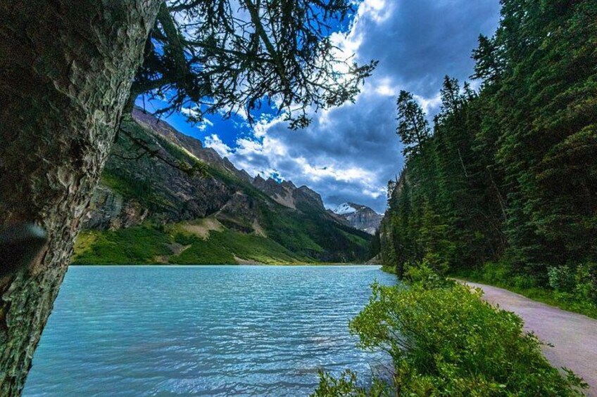 Ein See, umgeben von Bergen, ein bewaldeter Pfad und ein klarer Himmel. 2