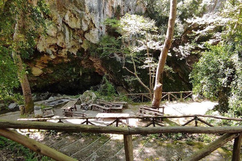 A wooden observation deck with benches overlooking a forested area with a rocky cliff in the background. 1